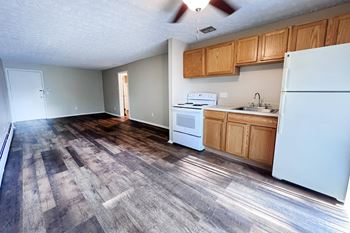 A kitchen with a white refrigerator, stove, and sink.